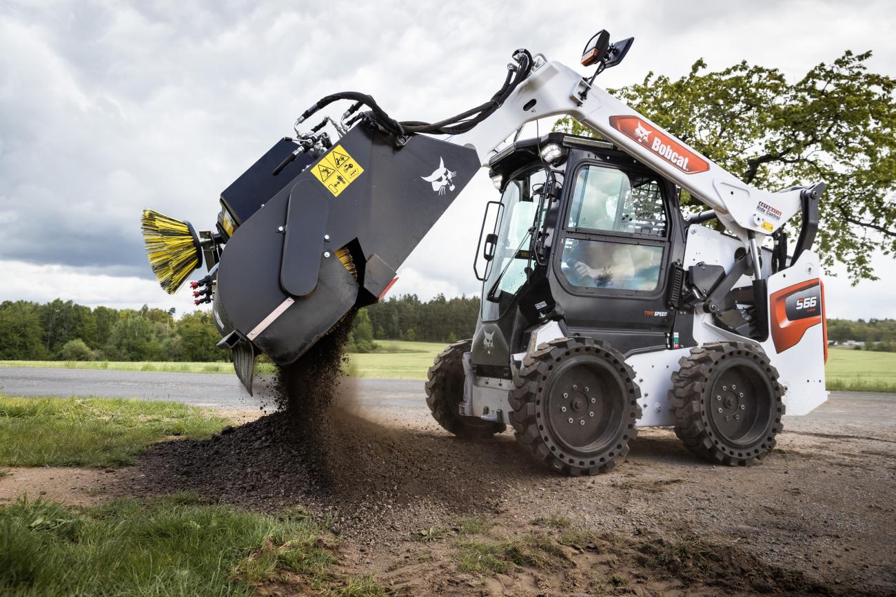 bobcat met bezem en opvangbak legen. 